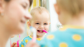 Toddler looking in mirror while brushing teeth