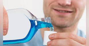 Person pouring mouthwash in cup