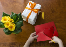 flower, present and kid cutting heart out of paper