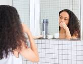 Woman brushing her teeth in mirror