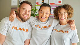 People smiling wearing volunteer shirts