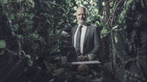 man in business attire in middle of jungle 