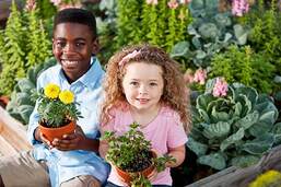 Two kids smiling holding plants