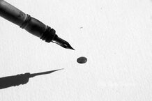 Pen making a black dot on piece of paper