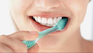 Picture of a person brushing their teeth with a green toothbrush