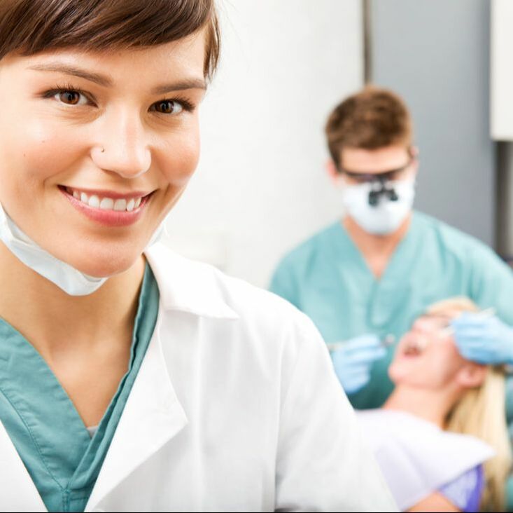 Hygienist with Dentist and Patient in Background